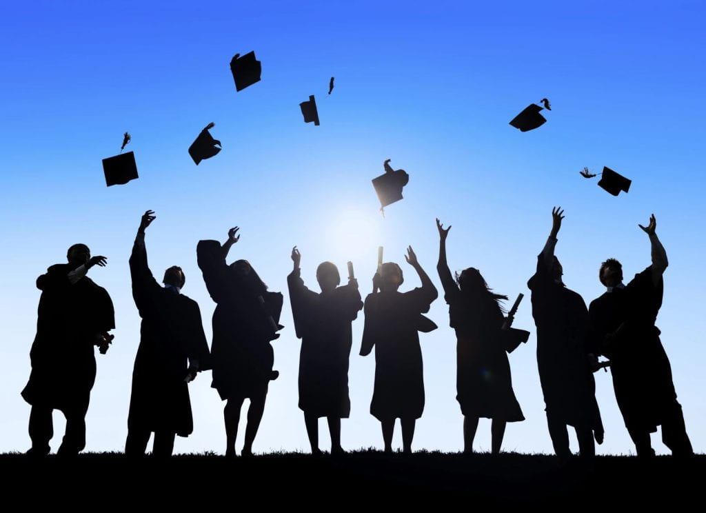 A silhouette of graduating students tossing their caps into the air.